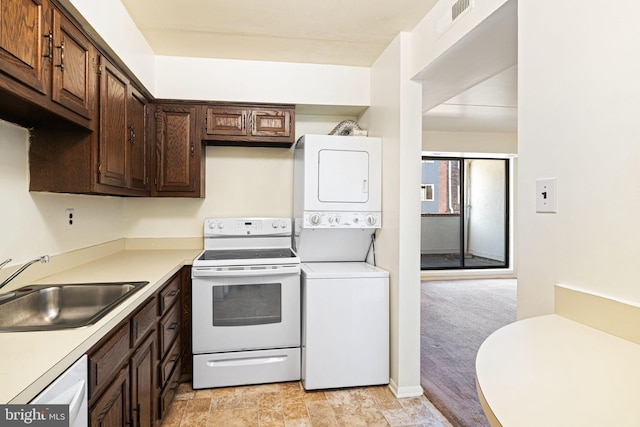 kitchen featuring white appliances, a sink, light countertops, dark brown cabinetry, and stacked washer and clothes dryer