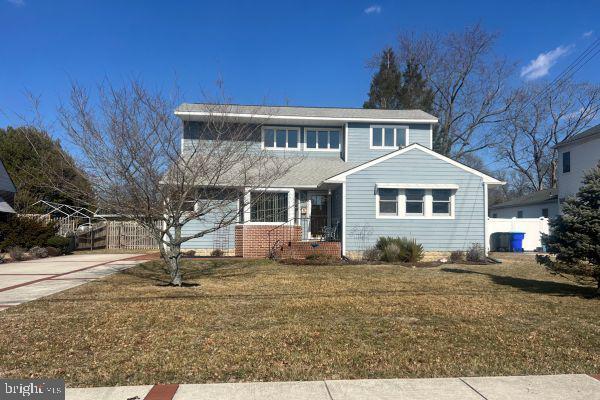 traditional-style house with fence, a front lawn, and concrete driveway