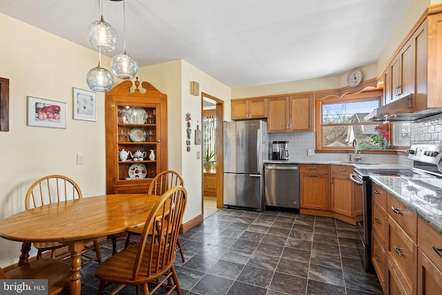 kitchen with tasteful backsplash, brown cabinets, decorative light fixtures, stainless steel appliances, and a sink