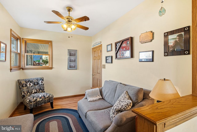 living area with baseboards, a ceiling fan, and wood finished floors