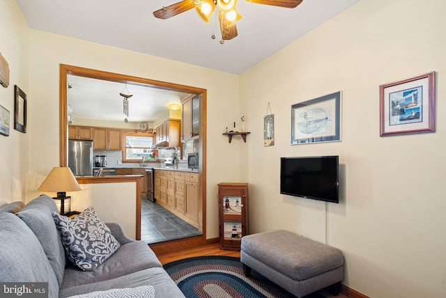 living room featuring ceiling fan, baseboards, and dark wood finished floors