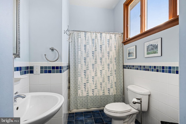 bathroom with a sink, tile walls, toilet, and tile patterned floors