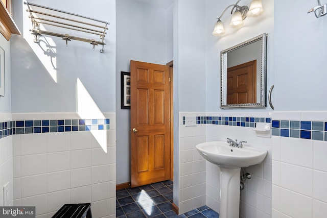 bathroom with a sink, a wainscoted wall, tile walls, and tile patterned floors