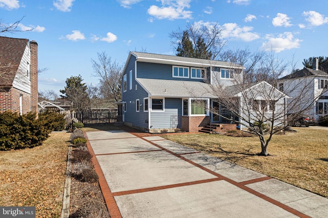 traditional-style home with concrete driveway, a shingled roof, a front yard, and fence