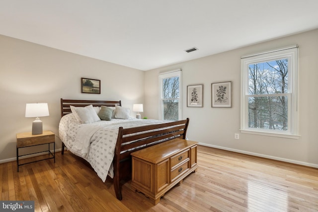 bedroom featuring light wood-type flooring, multiple windows, visible vents, and baseboards