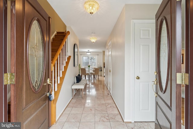 entryway with marble finish floor, baseboards, and stairs