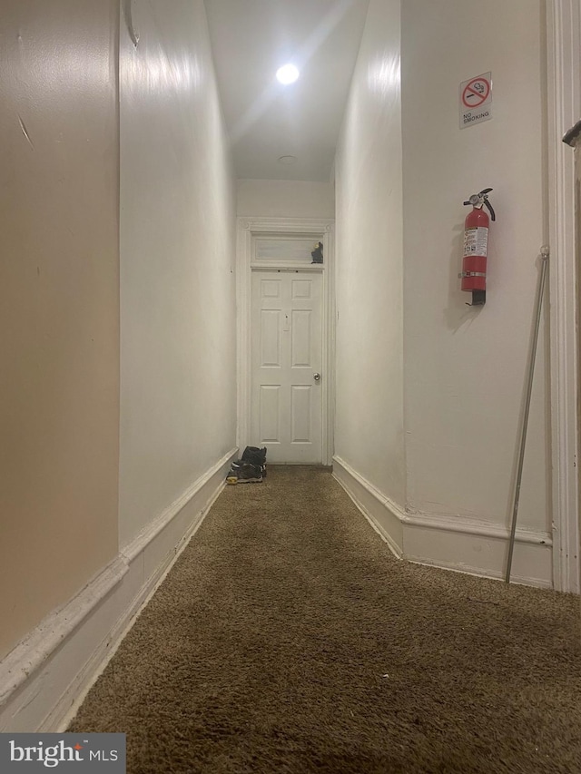 hallway with carpet floors and baseboards