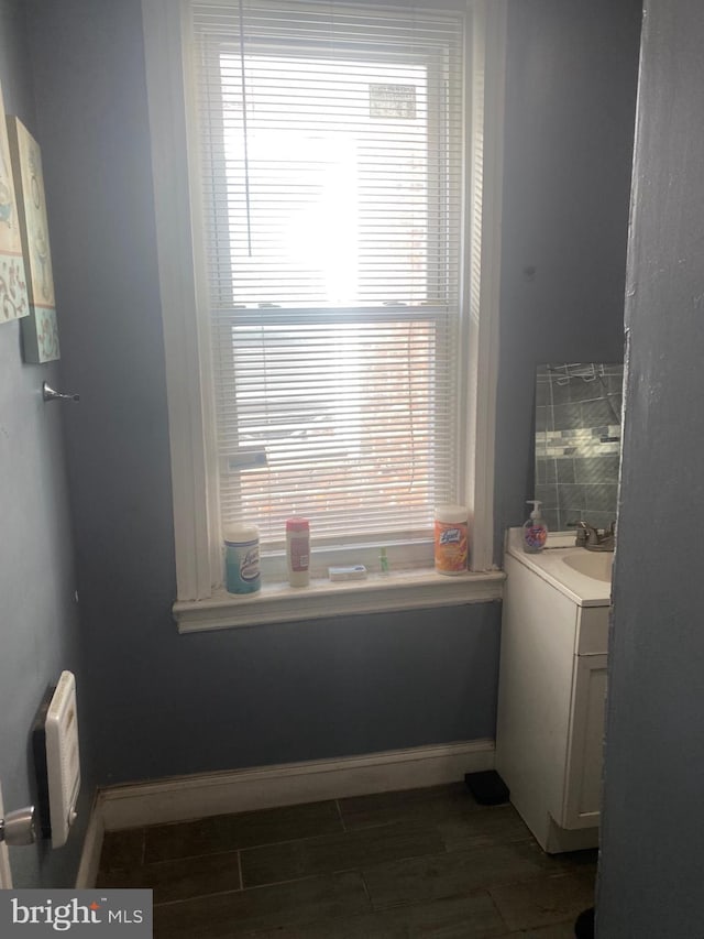 bathroom with wood finish floors, vanity, and baseboards