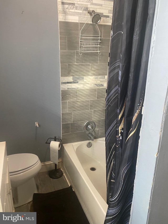 full bathroom featuring shower / tub combo, toilet, and baseboards