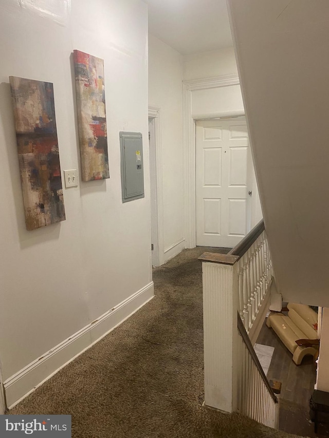 hall with dark colored carpet, stairway, electric panel, and baseboards