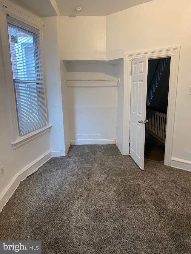 unfurnished bedroom featuring dark carpet and baseboards