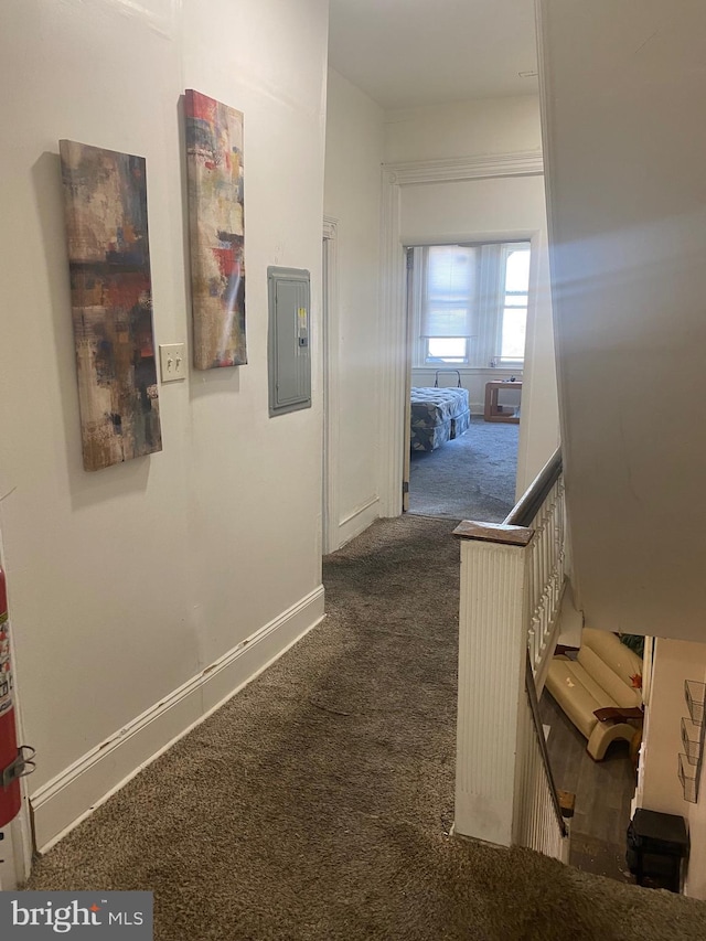 hallway featuring stairs, dark colored carpet, electric panel, and baseboards