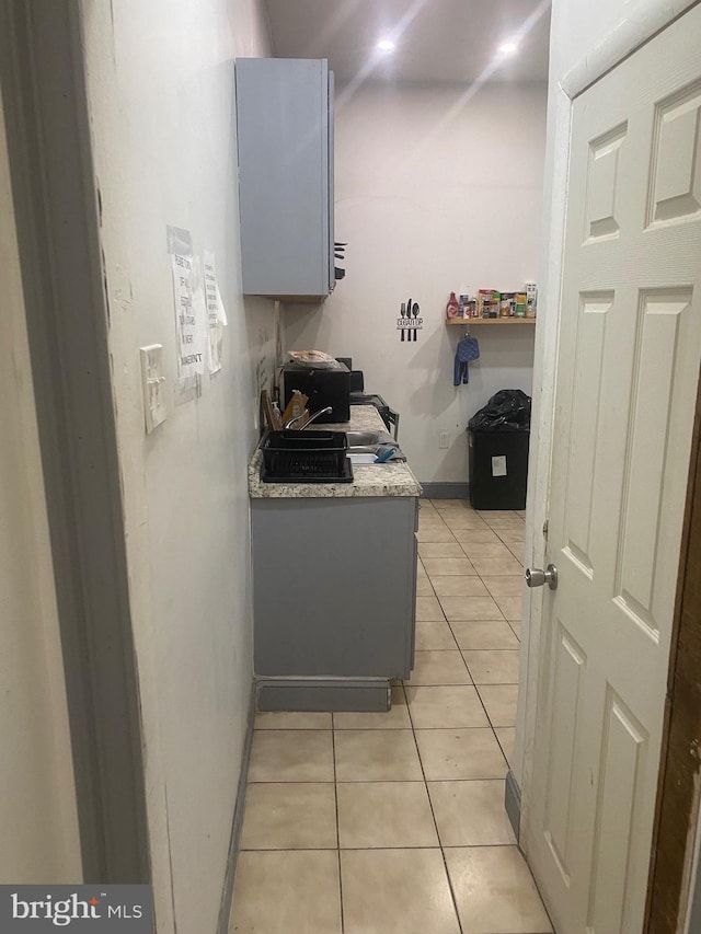 kitchen featuring light tile patterned floors, baseboards, gray cabinets, and light countertops