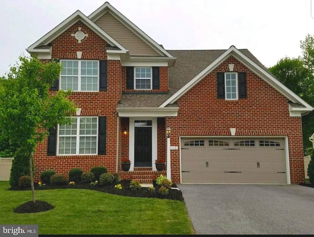 view of front of house featuring a garage, driveway, brick siding, and a front yard