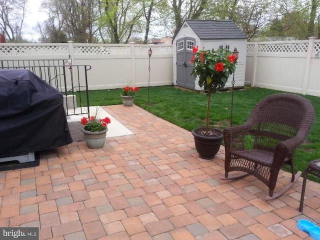 view of patio featuring an outbuilding, a fenced backyard, a storage shed, and area for grilling