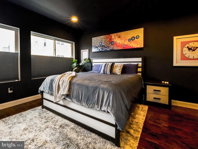 bedroom with dark wood-type flooring and baseboards