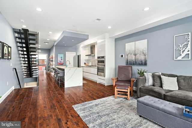 living area featuring baseboards, dark wood-type flooring, visible vents, and recessed lighting