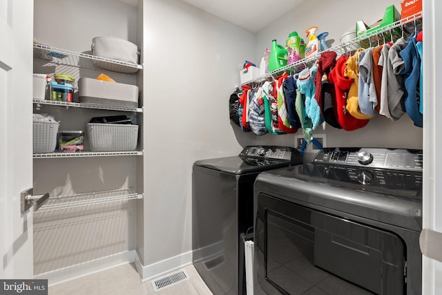 washroom featuring tile patterned flooring, laundry area, visible vents, baseboards, and washing machine and clothes dryer