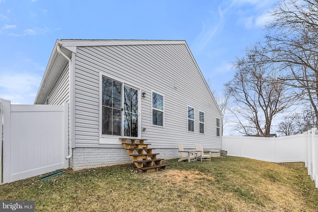 view of side of home featuring entry steps, a lawn, and fence