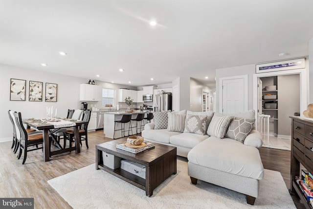 living room featuring recessed lighting, baseboards, and light wood finished floors