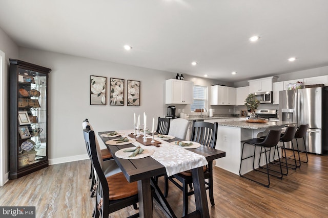 dining room with baseboards, wood finished floors, and recessed lighting