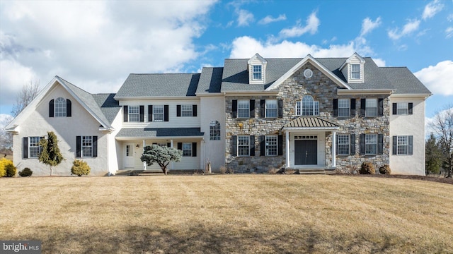 georgian-style home with a front yard and stone siding