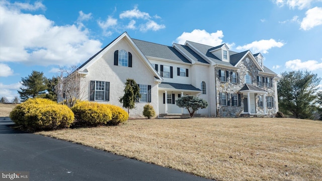 view of front facade with stone siding and a front lawn