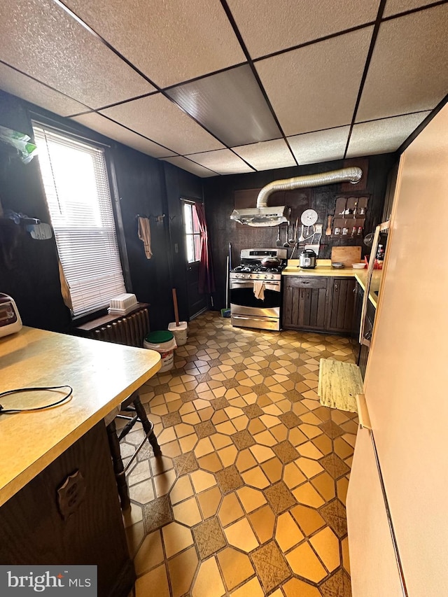 kitchen featuring stainless steel range with gas cooktop, light countertops, a paneled ceiling, and dark brown cabinets