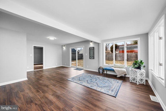 unfurnished living room featuring dark wood finished floors, visible vents, plenty of natural light, and baseboards