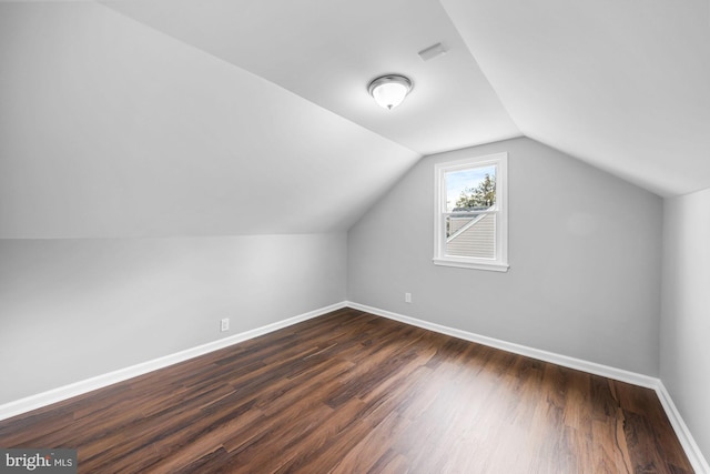 bonus room with dark wood-style floors, lofted ceiling, and baseboards