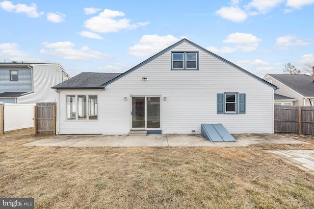 rear view of property featuring a patio area, a lawn, a fenced backyard, and roof with shingles