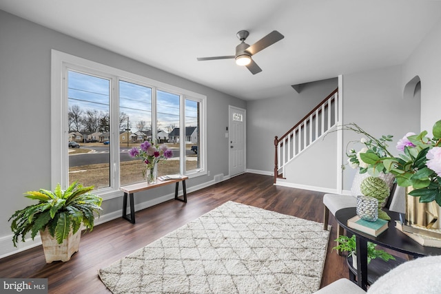 foyer entrance with baseboards, stairway, ceiling fan, and dark wood-type flooring