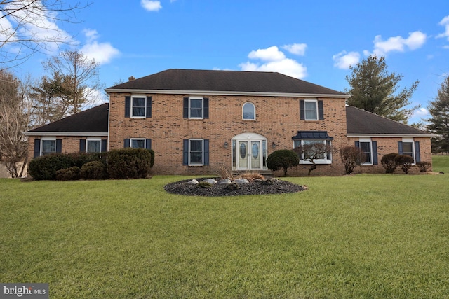 colonial house featuring a front lawn and brick siding