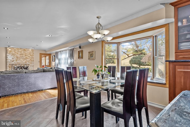 tiled dining space featuring ornamental molding, plenty of natural light, and a notable chandelier