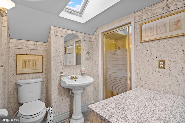 bathroom featuring vaulted ceiling with skylight, a shower with shower door, and toilet