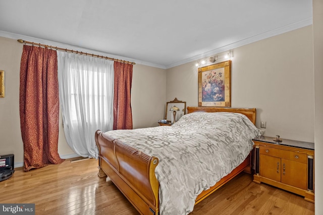 bedroom with ornamental molding and light wood-type flooring