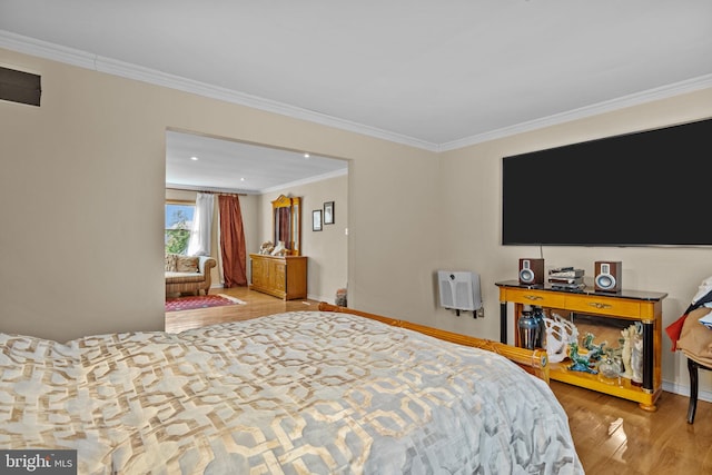 bedroom featuring light wood-type flooring, visible vents, crown molding, and baseboards