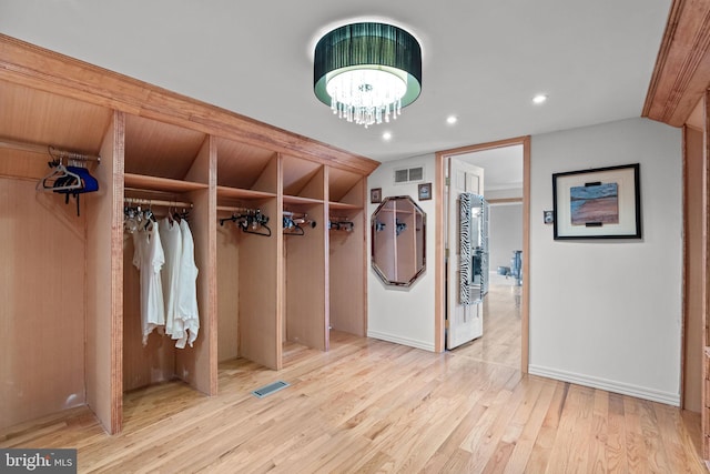 mudroom with vaulted ceiling, visible vents, a notable chandelier, and light wood-style flooring