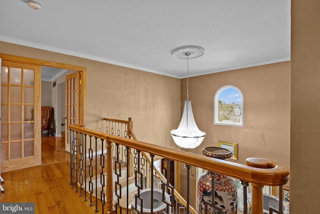 hall with ornamental molding, french doors, an upstairs landing, and wood finished floors