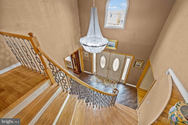 foyer with a chandelier, a towering ceiling, baseboards, and stairs