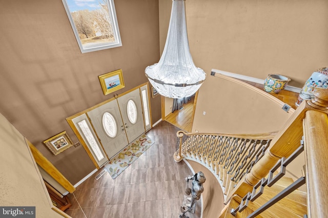 foyer with an inviting chandelier, visible vents, a high ceiling, and stairs