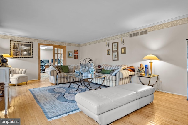 living area with ornamental molding, light wood-type flooring, visible vents, and baseboards