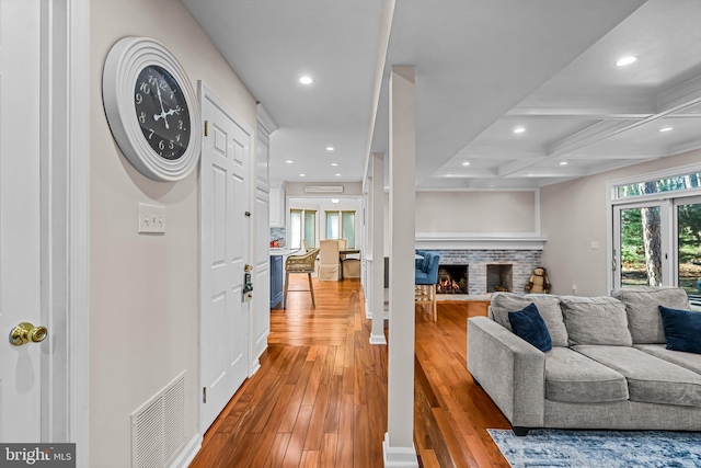 living area with visible vents, coffered ceiling, light wood-type flooring, a brick fireplace, and recessed lighting