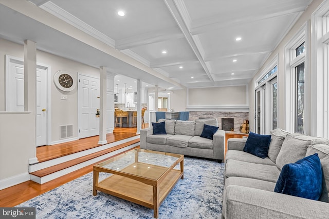 living room featuring visible vents, coffered ceiling, wood finished floors, and decorative columns