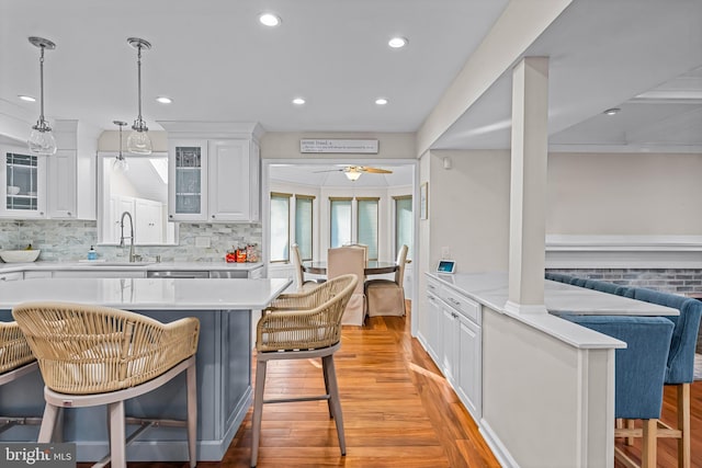 kitchen with white cabinets, a kitchen bar, light countertops, and a sink