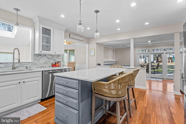 kitchen with gray cabinetry, a sink, white cabinetry, light wood-style floors, and stainless steel dishwasher