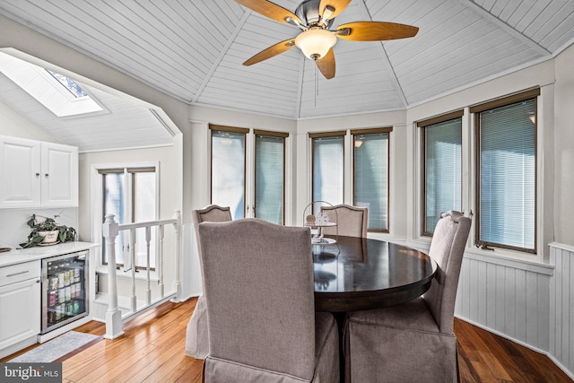 dining room with lofted ceiling with skylight, wood ceiling, beverage cooler, and light wood finished floors