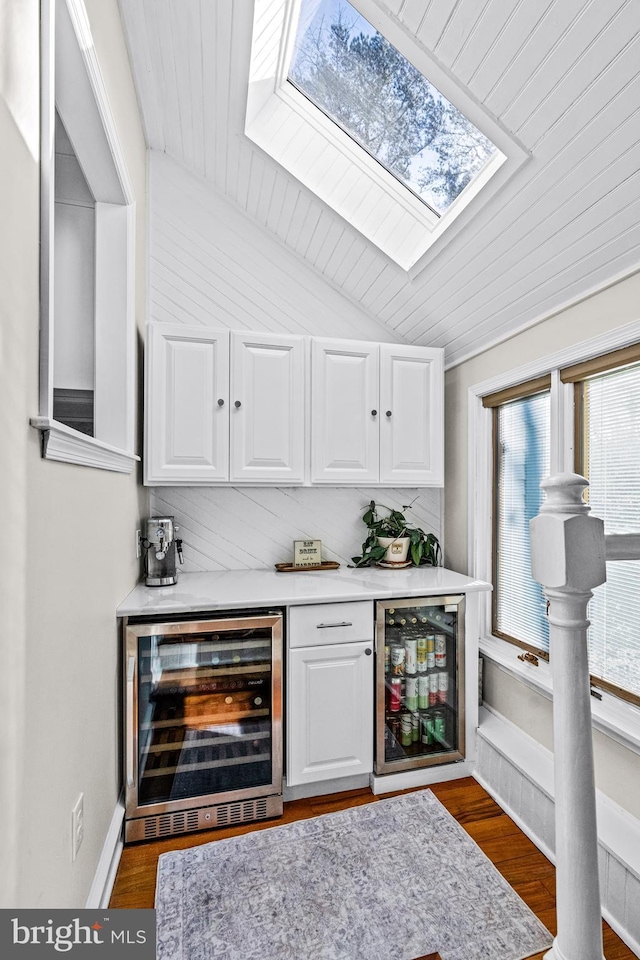 bar featuring wine cooler, vaulted ceiling, a bar, and wood finished floors