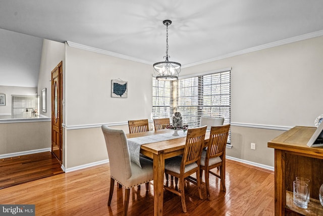 dining space featuring a notable chandelier, crown molding, baseboards, and wood finished floors