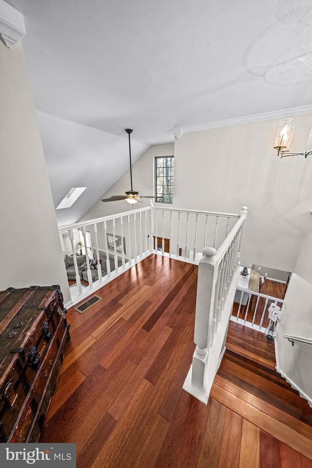 staircase featuring ceiling fan, hardwood / wood-style floors, lofted ceiling with skylight, and visible vents